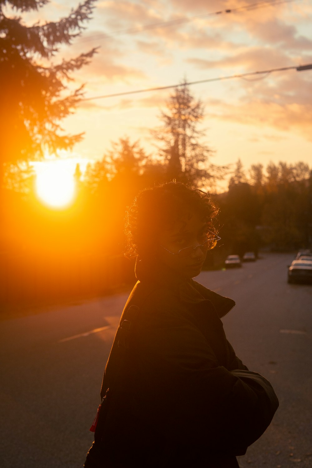 a person standing on the side of a road at sunset