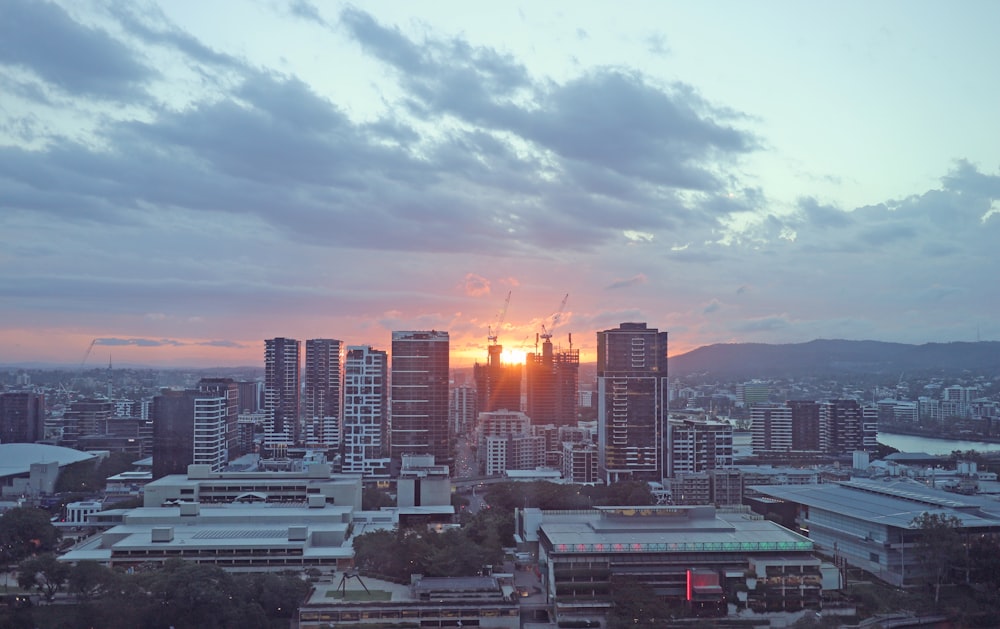 the sun is setting over a city with tall buildings