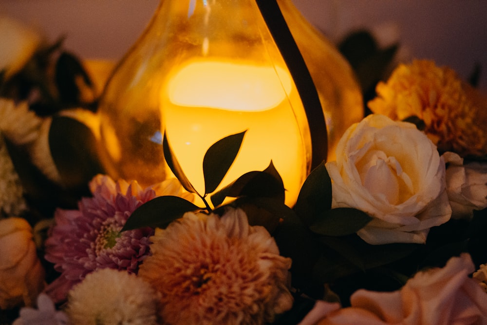 a vase filled with flowers next to a lit candle