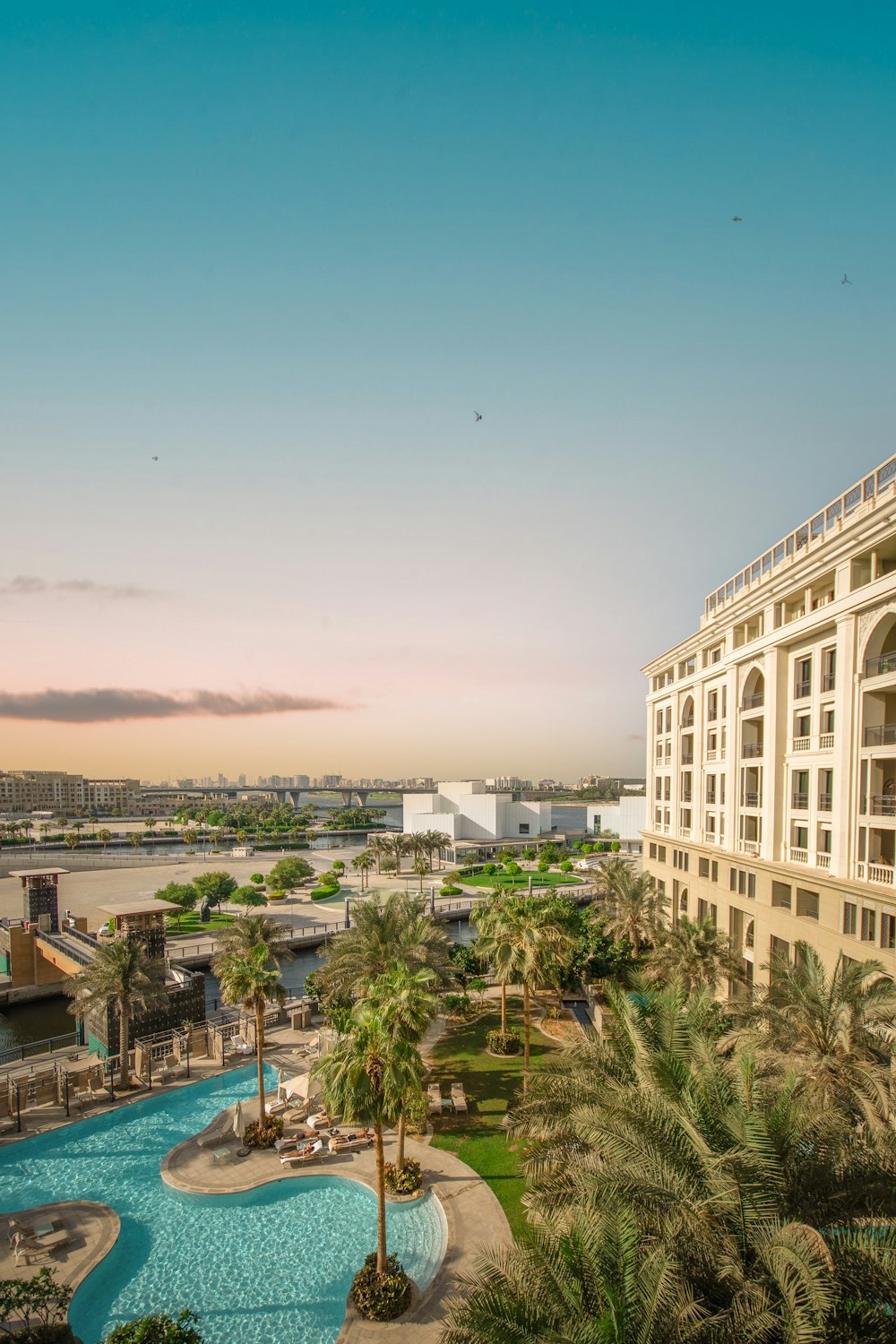 a hotel with a pool and palm trees in front of it