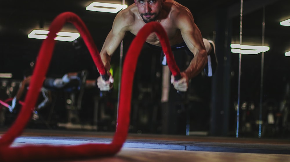 a man doing a push up on a red rope