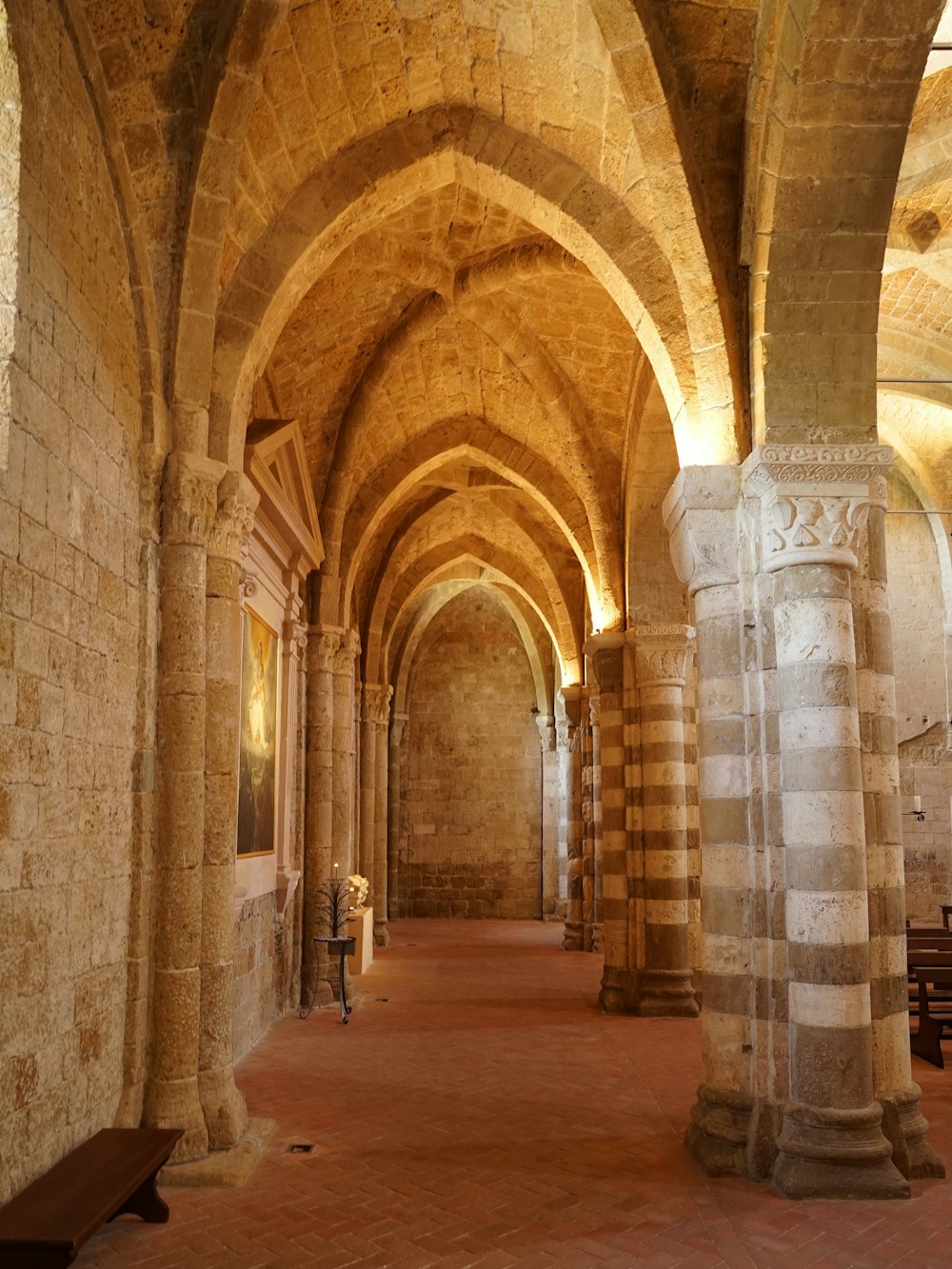 um longo corredor com arcos de pedra e bancos