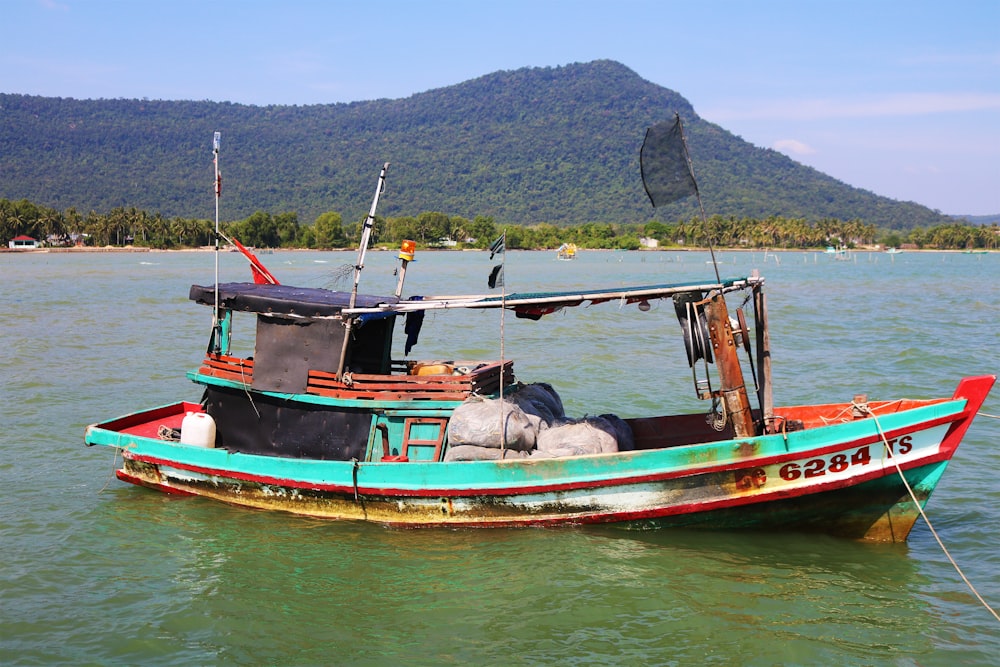 a blue and red boat floating on top of a body of water