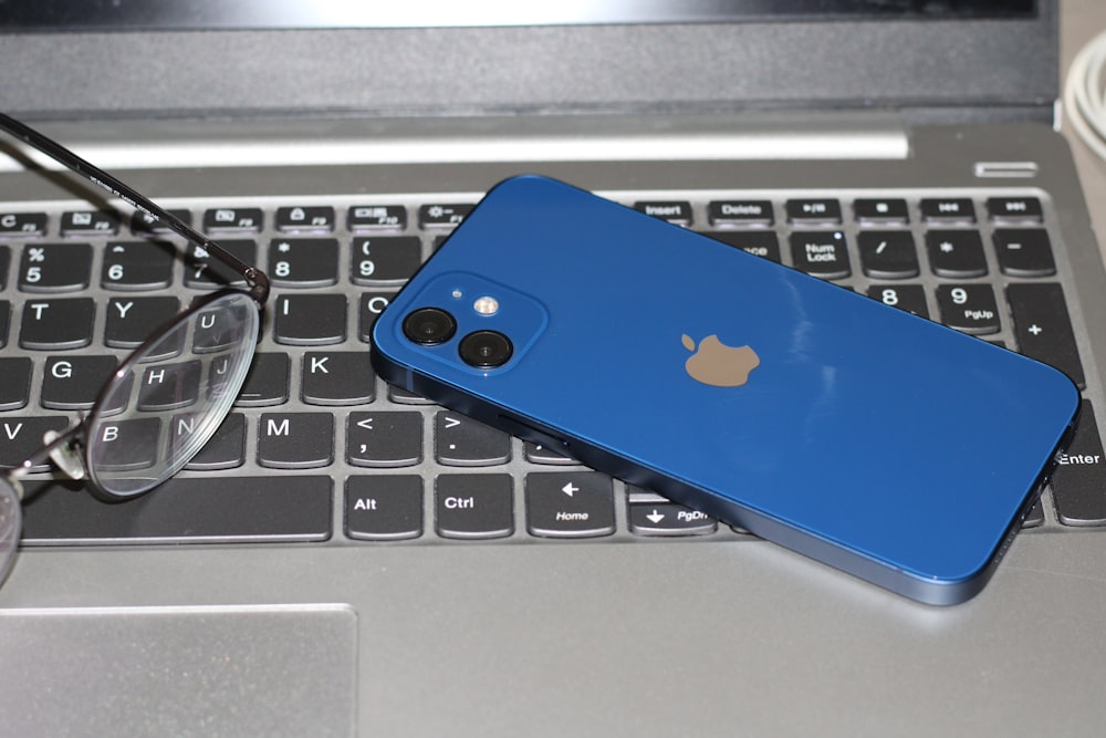 a blue iphone sitting on top of a laptop computer