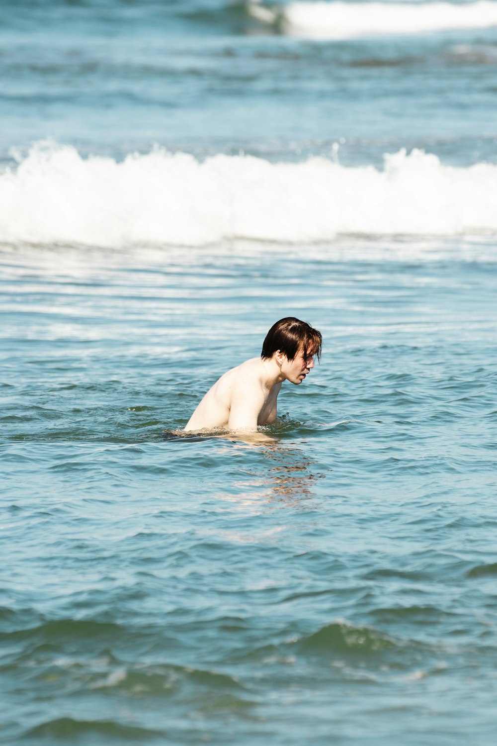 a man swimming in the ocean with a surfboard
