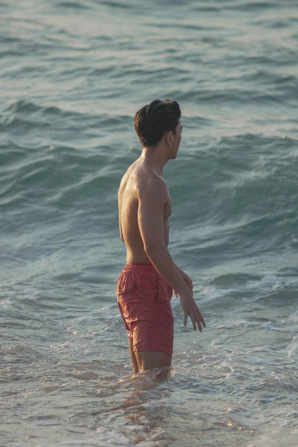 a man standing in the ocean with a frisbee