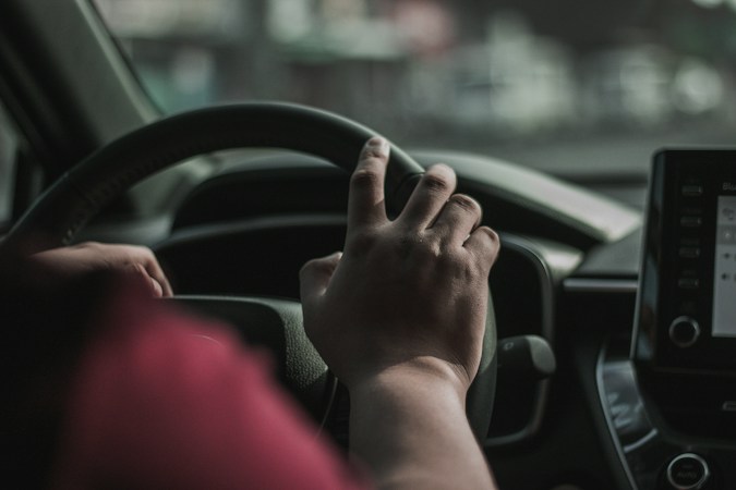 A driver's hand resting on a steering wheel, a reminder for Las Vegas teen drivers to keep both hands on the wheel and phones away in school zones