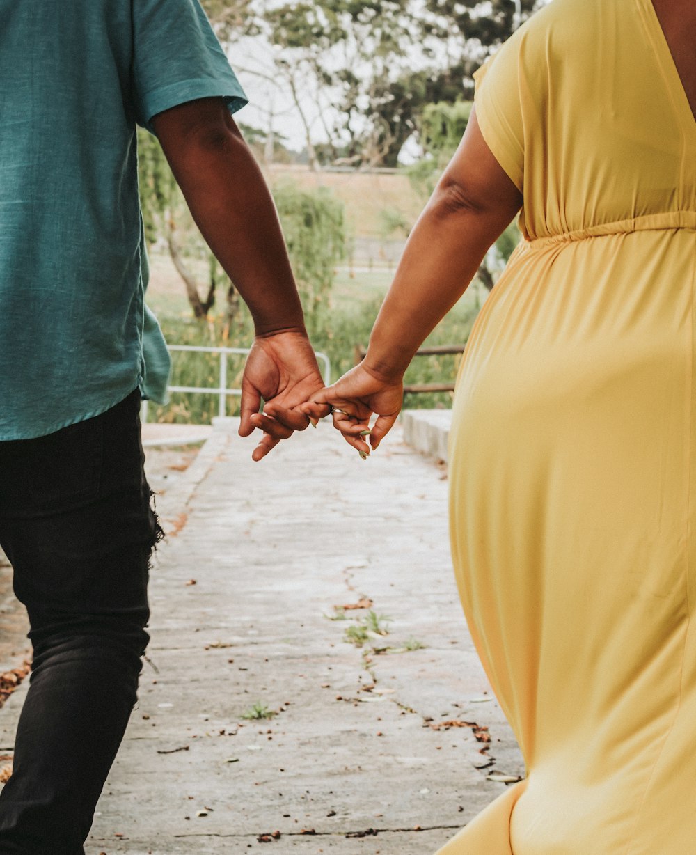 a man and a woman walking down a sidewalk holding hands