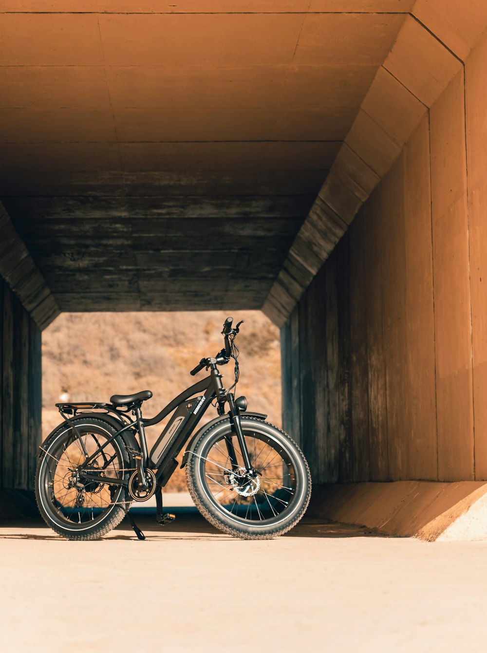 a bicycle parked in a tunnel under a bridge