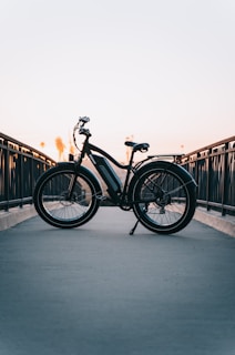 a bicycle parked on a bridge at sunset