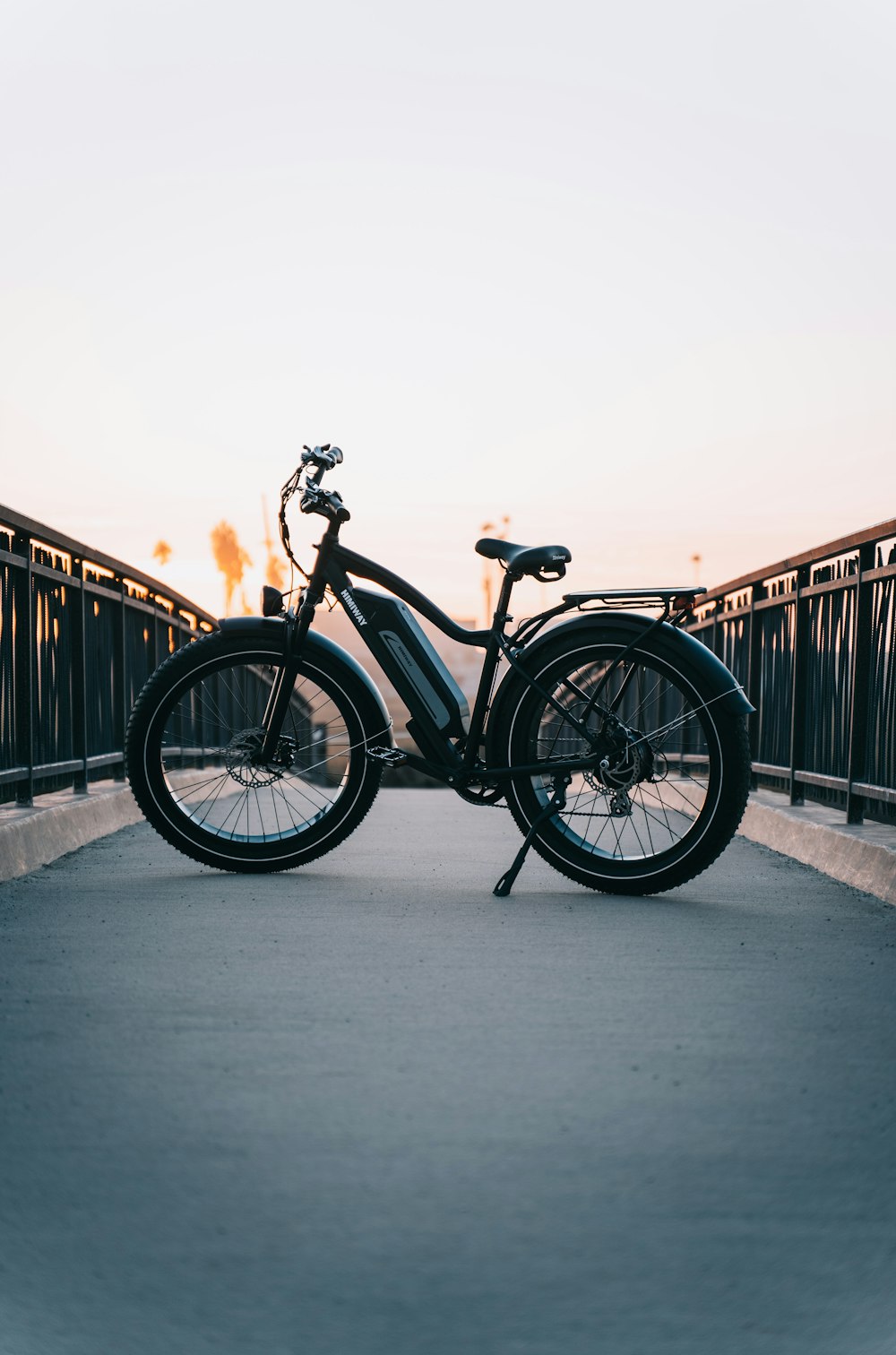 a bicycle parked on a bridge at sunset