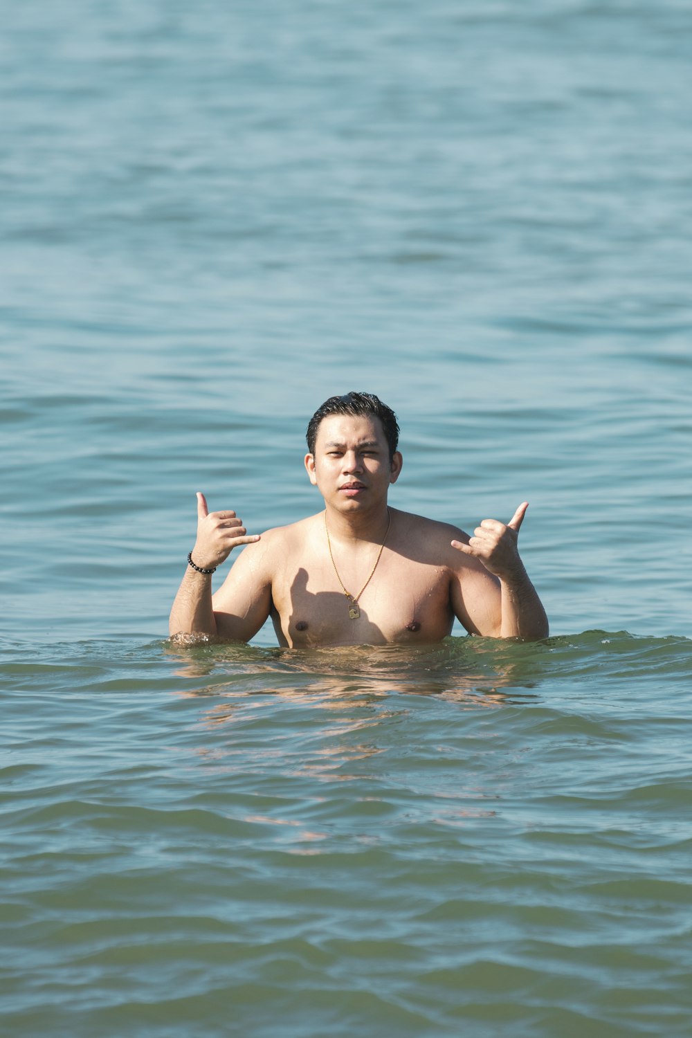 a man standing in the water giving a peace sign