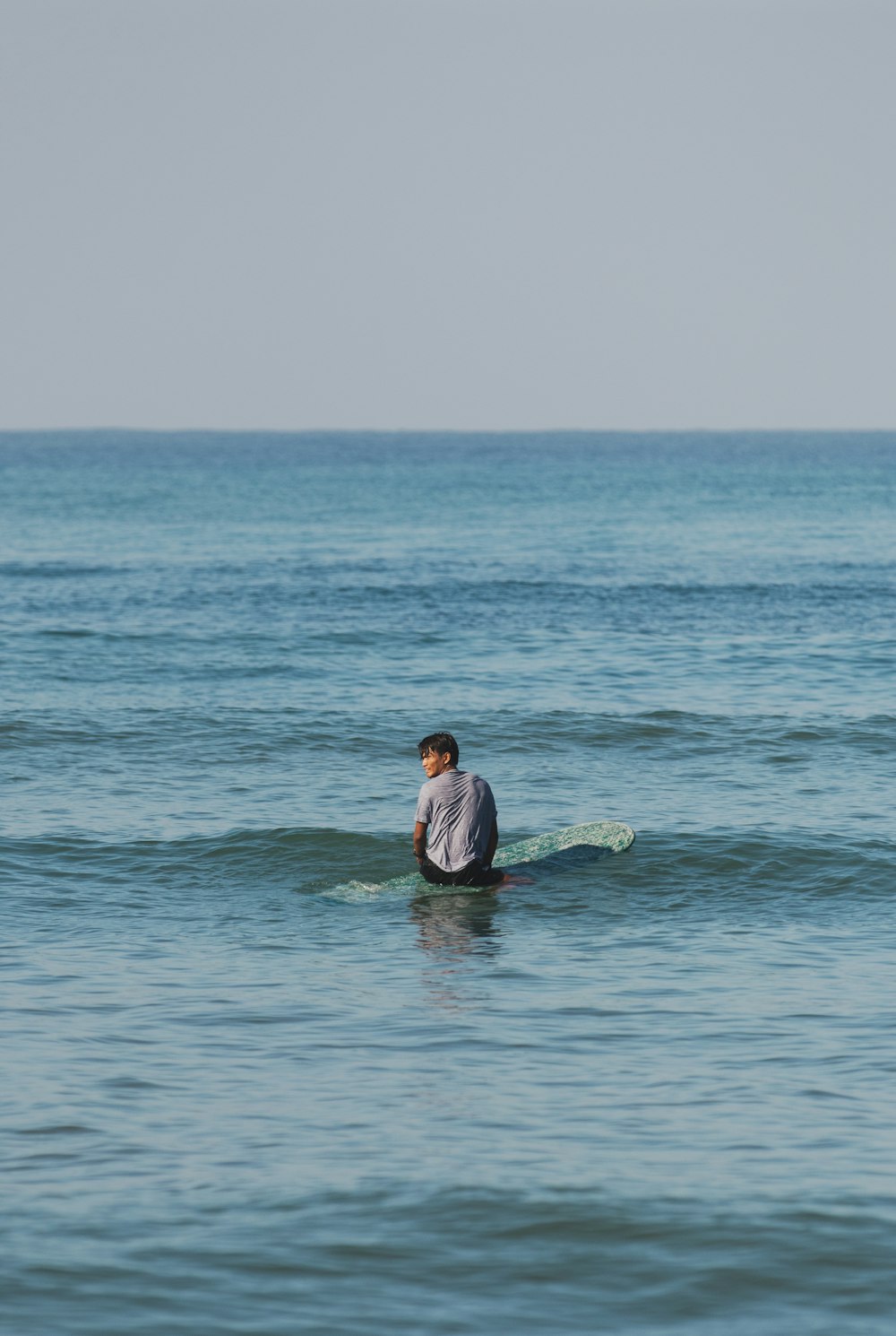 a man sitting on a surfboard in the ocean