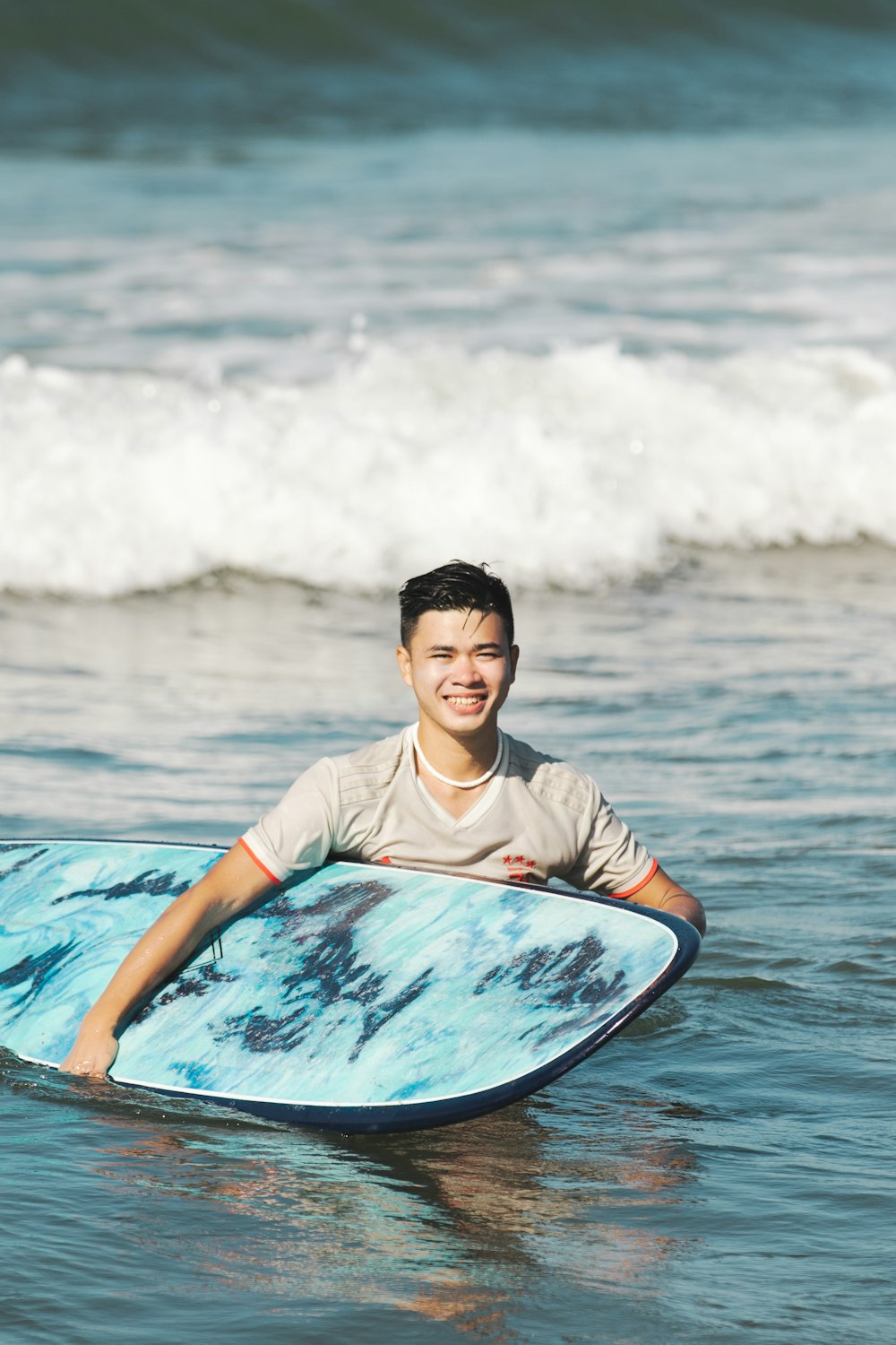 a man smiles while holding a surfboard in the ocean