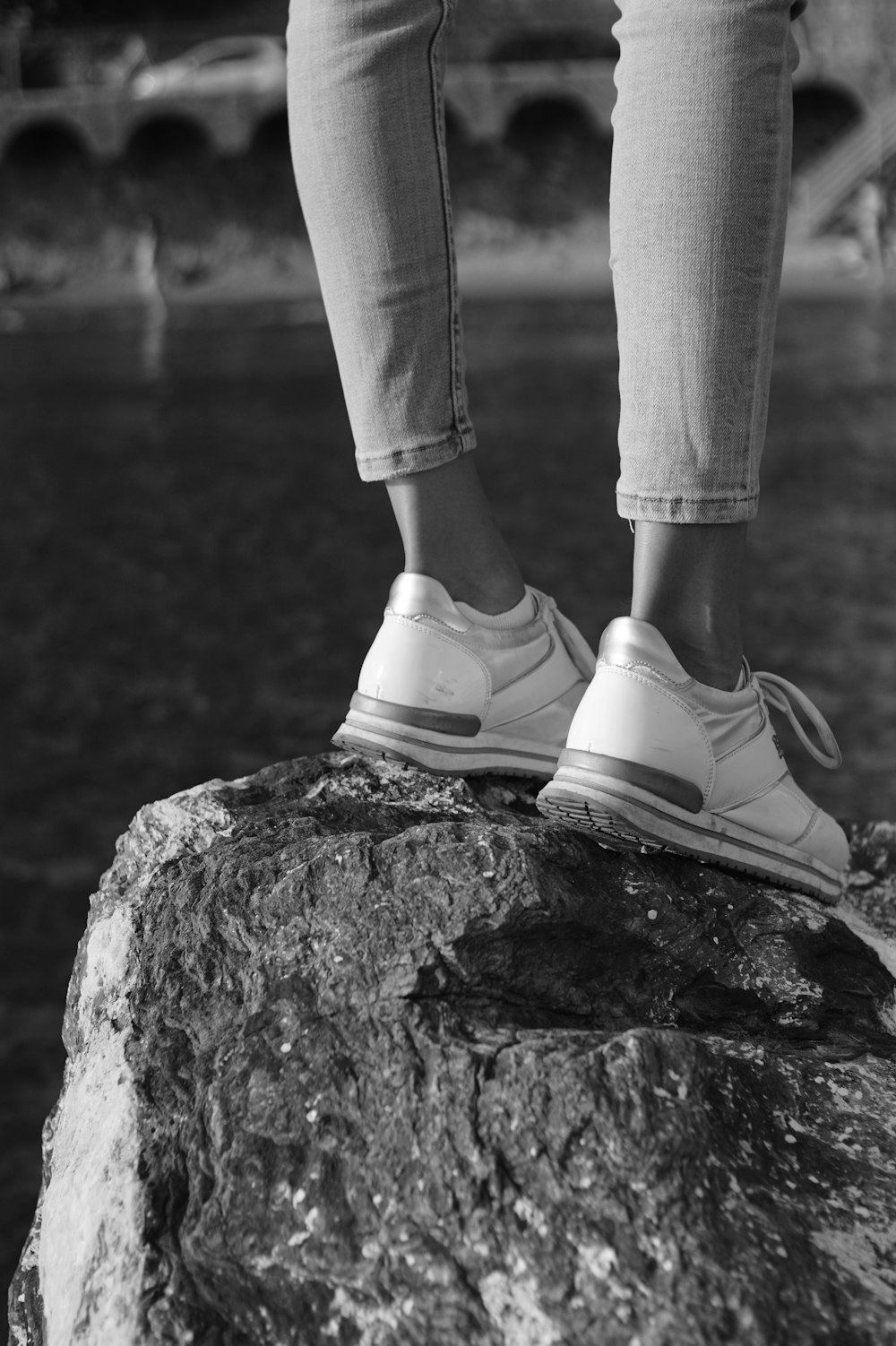 a person standing on top of a rock next to a body of water