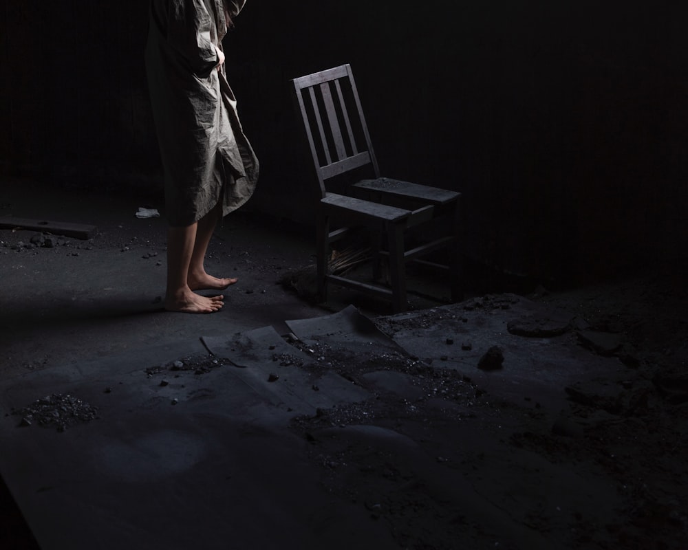 a person standing next to a chair in a dark room