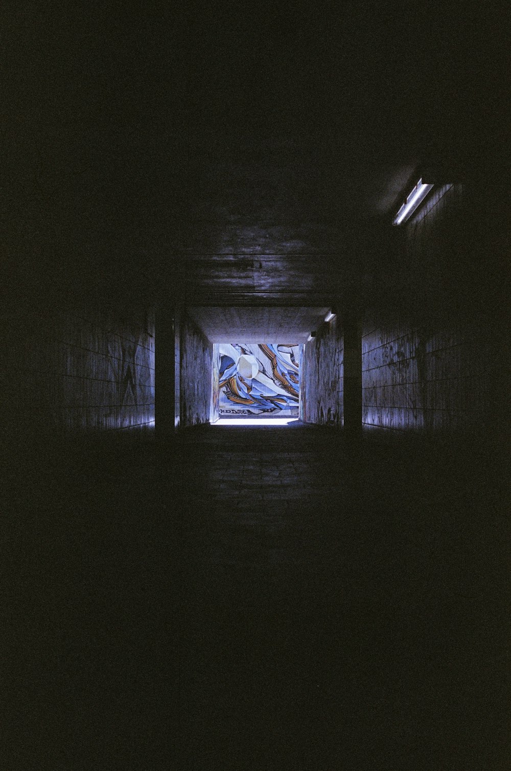 a dark tunnel with a painting on the wall