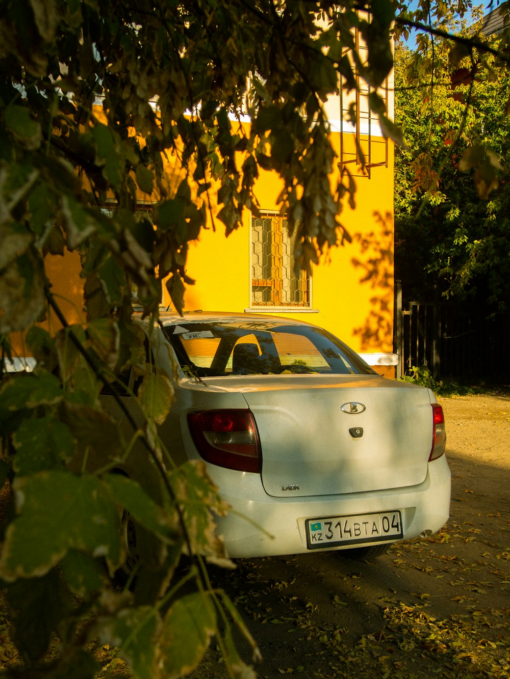 a white car parked in front of a yellow house