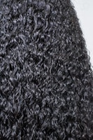 Close-up of vibrant, tightly coiled natural curls shining under soft light.