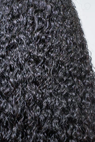 Close-up of natural hair styled in vibrant coils, glowing softly against a bright gradient background.
