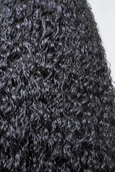 Beautiful curls shining under soft light, surrounded by natural ingredients like shea butter and oils.