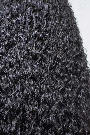 Close-up of natural curly hair with vibrant curls and healthy shine under soft salon lighting.