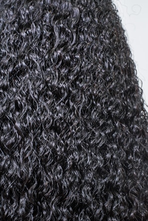 Close-up of vibrant, tightly coiled natural curls shining under soft light.