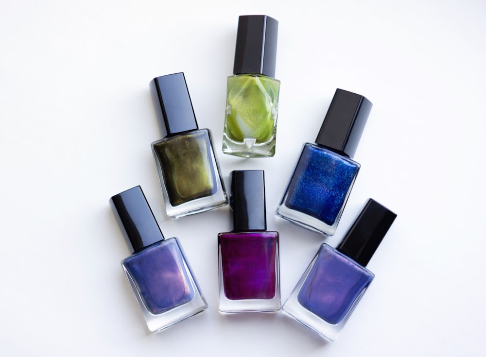 a group of five different colored nail polishes