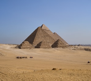 a group of people riding camels in front of a pyramid