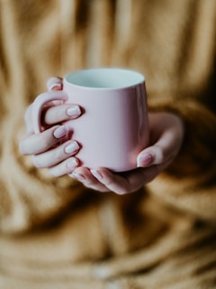 a woman holding a pink coffee cup in her hands