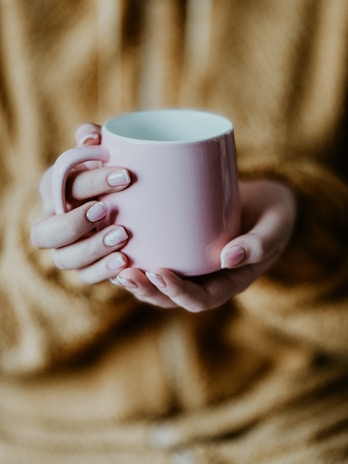 a woman holding a pink coffee cup in her hands