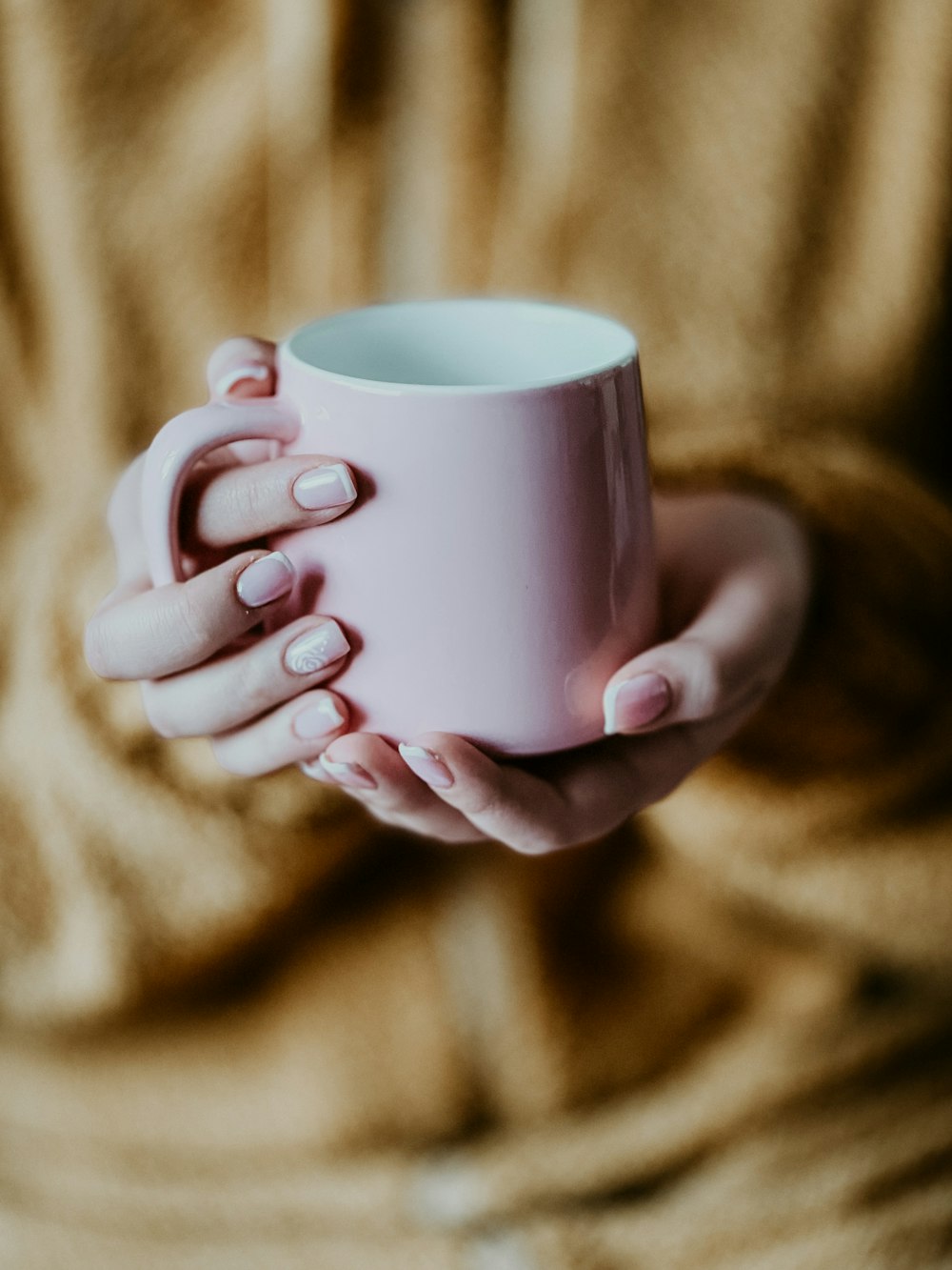 a woman holding a pink coffee cup in her hands