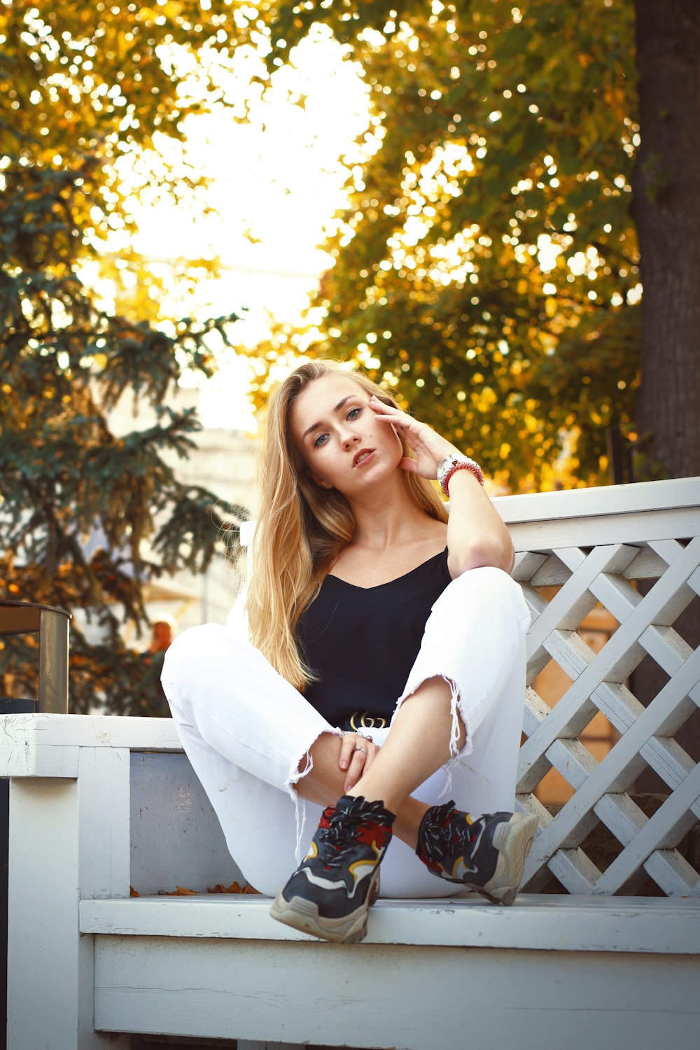 a beautiful young woman sitting on a white bench