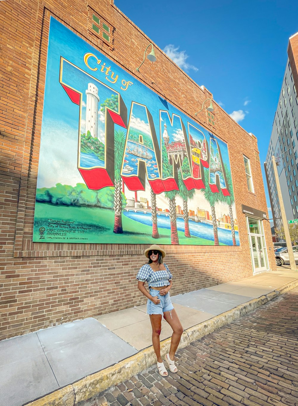 a woman standing in front of a building with a mural on it