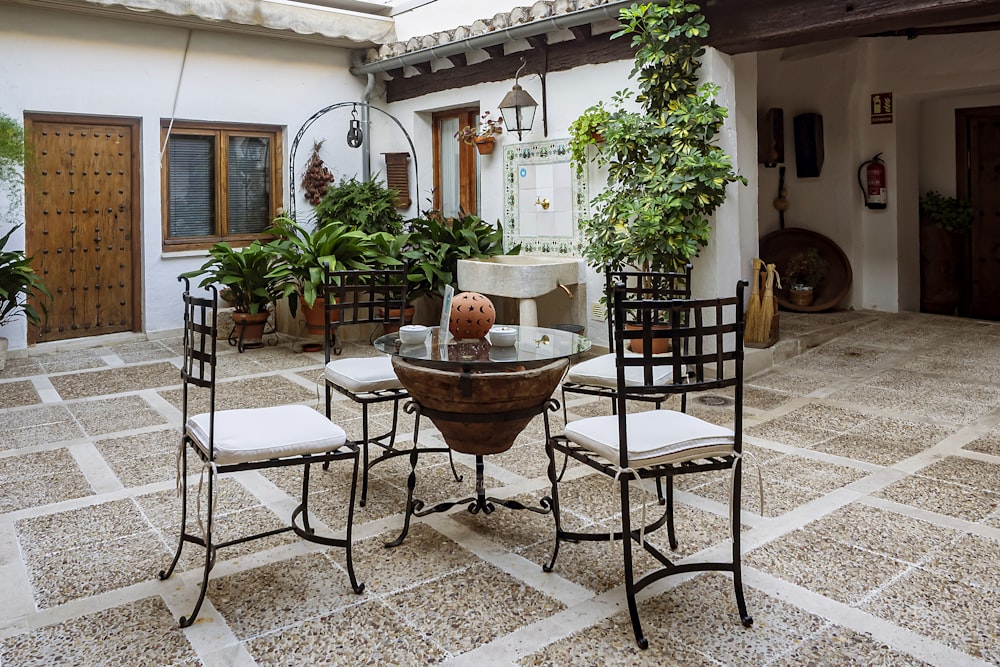 a patio with a table and chairs and potted plants