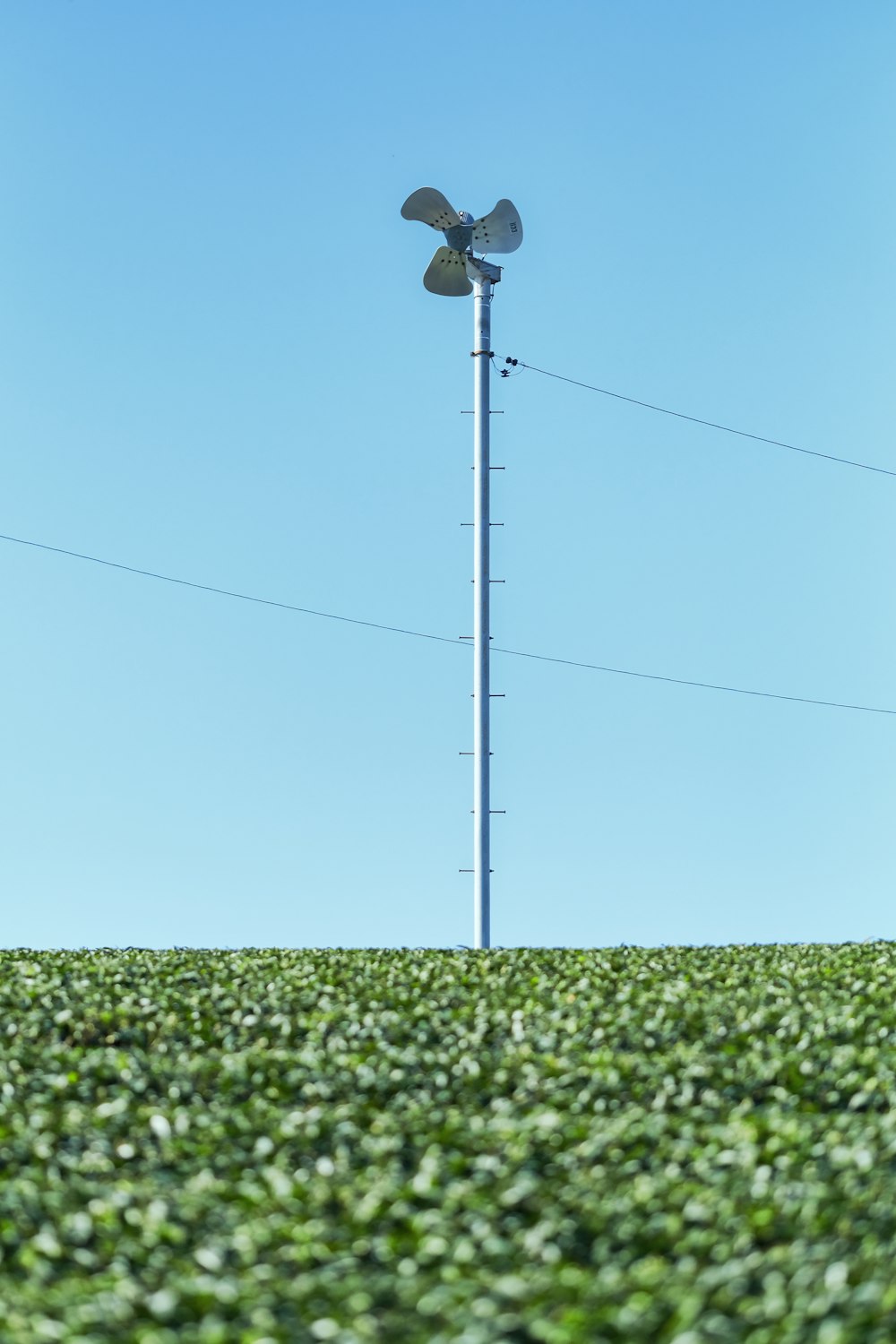 a windmill on top of a tall pole in the middle of a field