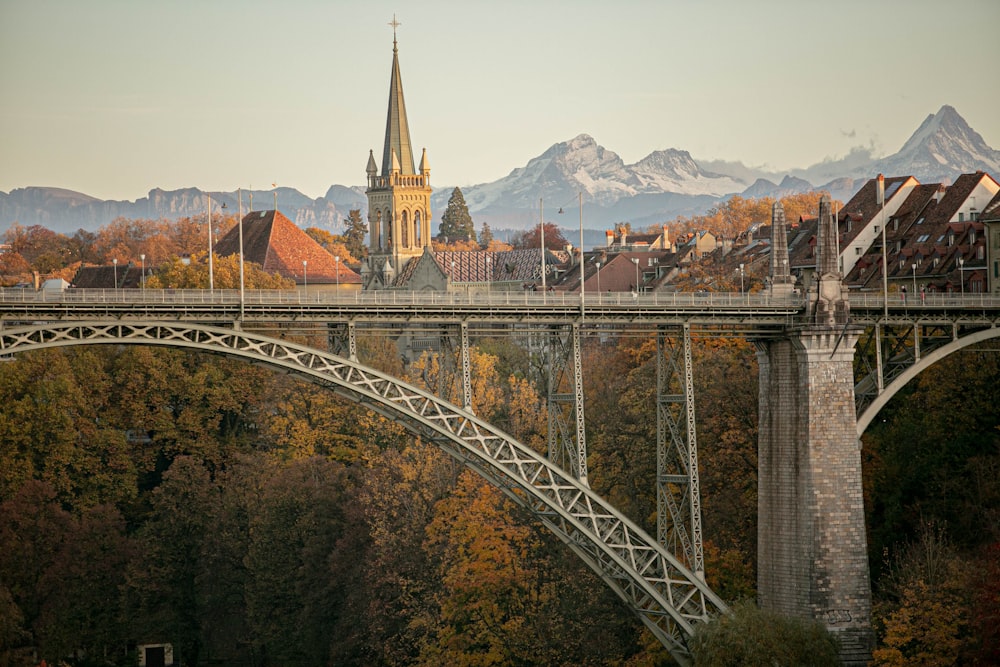 a bridge over a river with a church steeple in the background