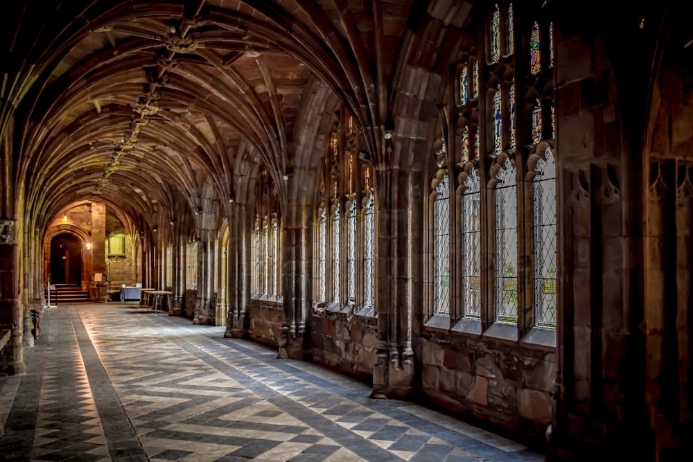 a long hallway with a checkered floor and arched windows