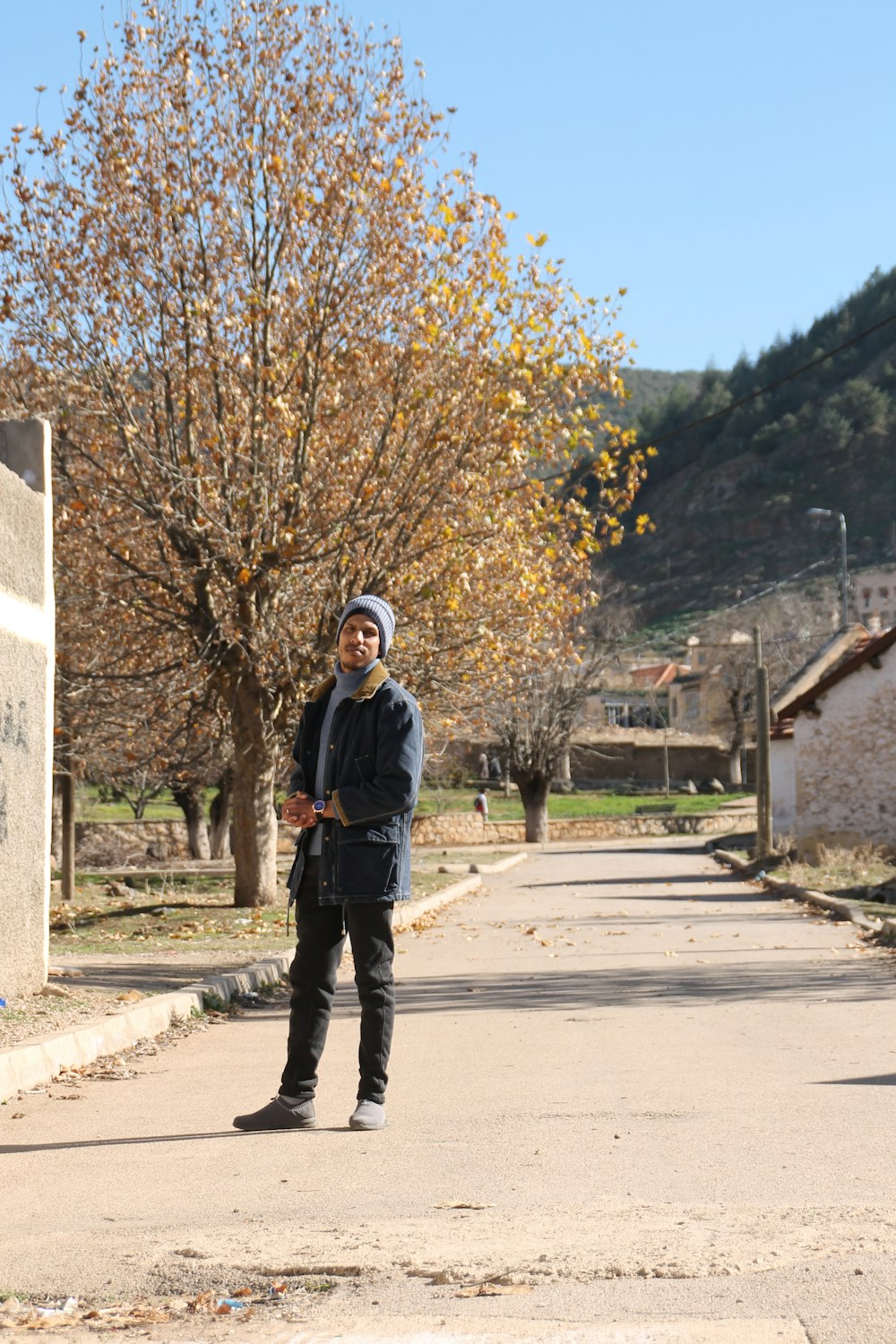 a man standing on the side of a road next to a tree