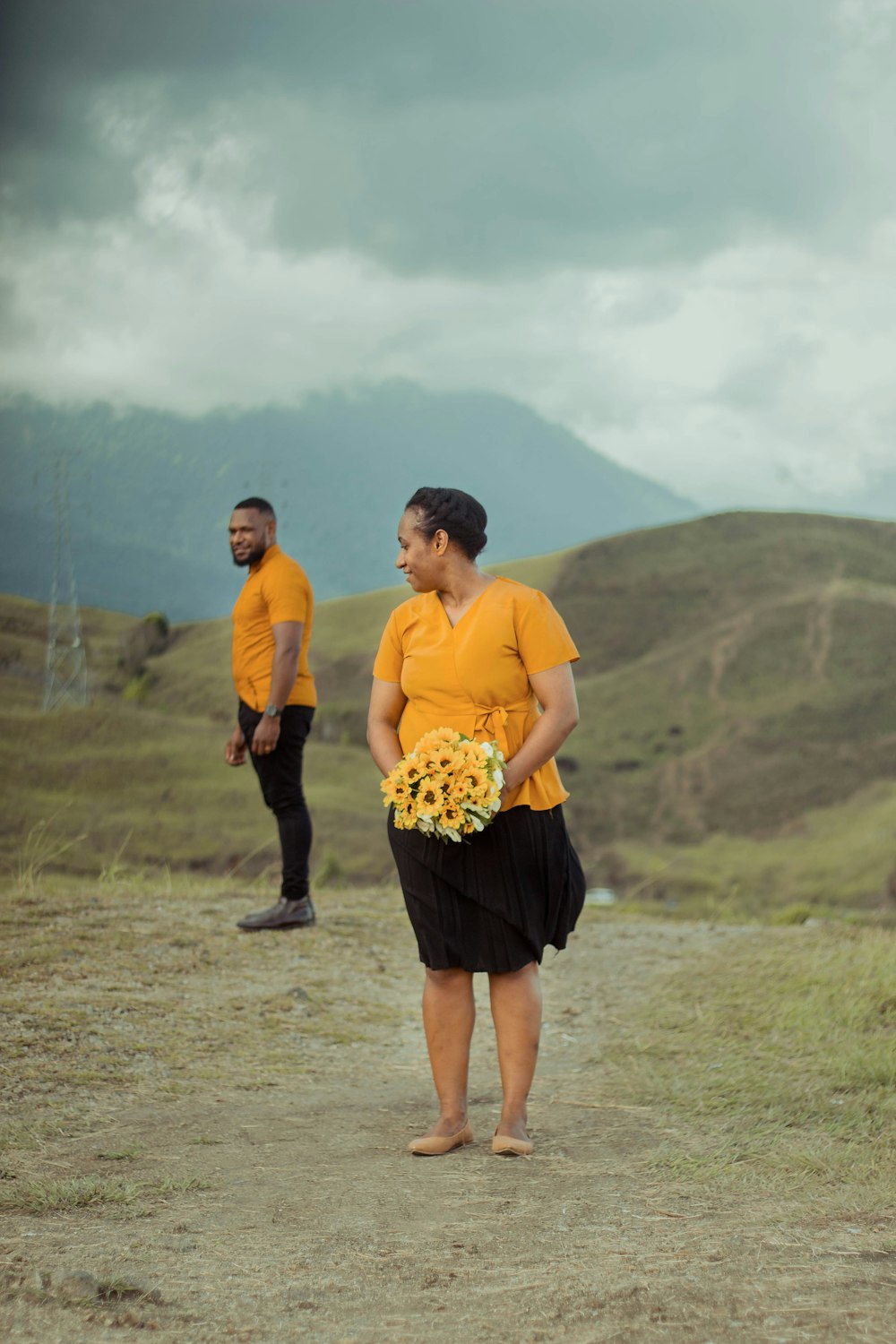 a man and a woman standing on a dirt road