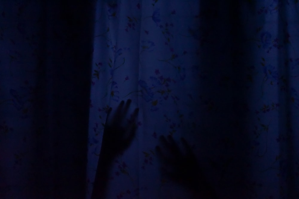 a person's hand reaching out from behind a curtain