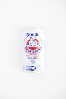 A white can of Nestlé Bear Brand ready-to-drink milk with a logo featuring a bear holding a glass. The can includes text in both English and Indonesian, indicating it is sterile milk.