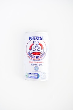 A white can of Nestlé Bear Brand ready-to-drink milk with a logo featuring a bear holding a glass. The can includes text in both English and Indonesian, indicating it is sterile milk.