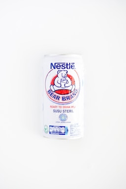 A white can of Nestlé Bear Brand ready-to-drink milk with a logo featuring a bear holding a glass. The can includes text in both English and Indonesian, indicating it is sterile milk.