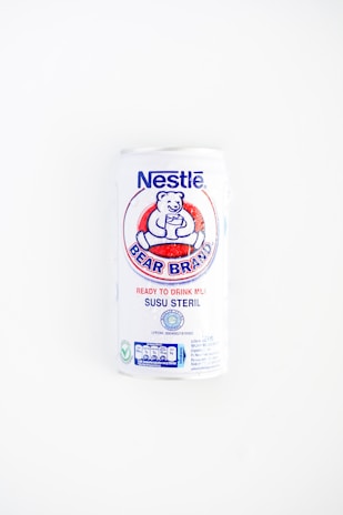 A white can of Nestlé Bear Brand ready-to-drink milk with a logo featuring a bear holding a glass. The can includes text in both English and Indonesian, indicating it is sterile milk.