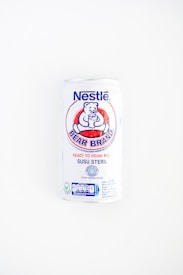 A white can of Nestl&eacute; Bear Brand ready-to-drink milk with a logo featuring a bear holding a glass. The can includes text in both English and Indonesian, indicating it is sterile milk.