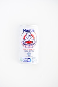 A white can of Nestlé Bear Brand ready-to-drink milk with a logo featuring a bear holding a glass. The can includes text in both English and Indonesian, indicating it is sterile milk.