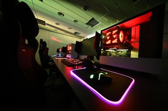 a computer desk with neon lights in a dark room