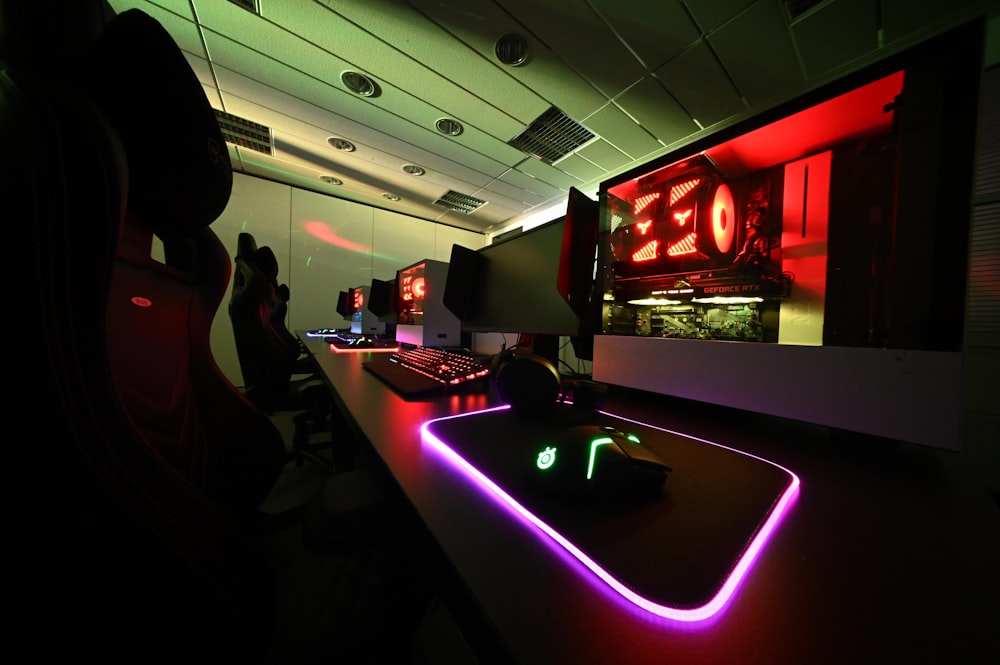 a computer desk with neon lights in a dark room