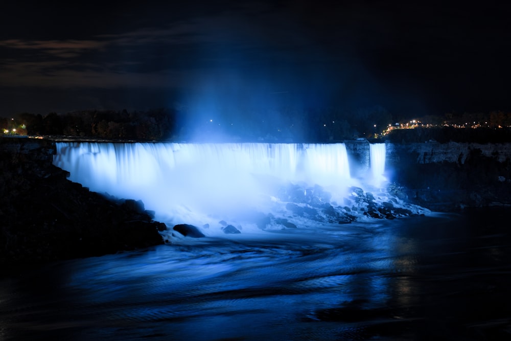 a large waterfall is lit up at night